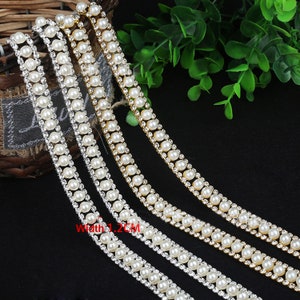 May include: Three rows of white pearl and rhinestone trim, each row is approximately 1.2 cm wide. The trim is made of small white pearls and clear rhinestones.