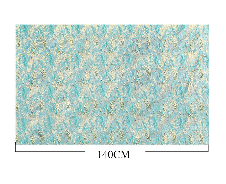 May include: A rectangular fabric with a textured pattern in shades of teal, cream, and gold. The fabric measures 140cm in width. The design features an abstract, mottled appearance, suitable for various craft projects.