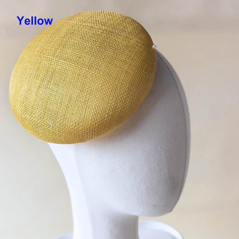 May include: A yellow, oval-shaped hat with a textured surface. The word "Yellow" is printed in blue in the upper left corner. The hat is displayed on a white mannequin head.