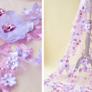May include: Purple and white floral lace fabric with 3D flowers. The fabric is sheer and delicate, with a soft, romantic feel.