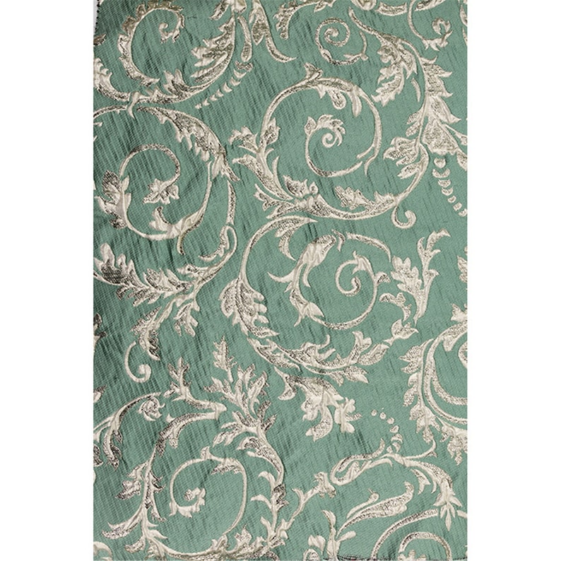 May include: Teal fabric with a silver metallic floral pattern. The fabric has a textured, woven look.