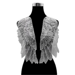 May include: White lace angel wings with a delicate, feathered design. The wings are attached to a mannequin and are perfect for adding a touch of whimsy to any project.