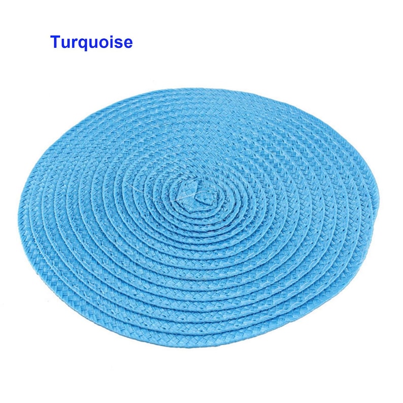 May include: A round, turquoise placemat with a woven texture. The placemat is circular, with a spiral pattern emanating from the center. The word "Turquoise" is printed in the upper left corner.
