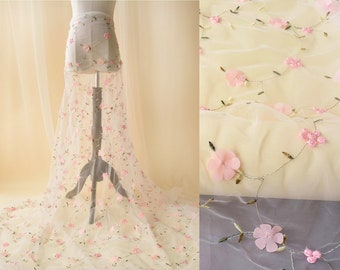 May include: White tulle fabric with pink embroidered flowers and leaves. The fabric is draped over a stand and a close-up of the fabric is shown.