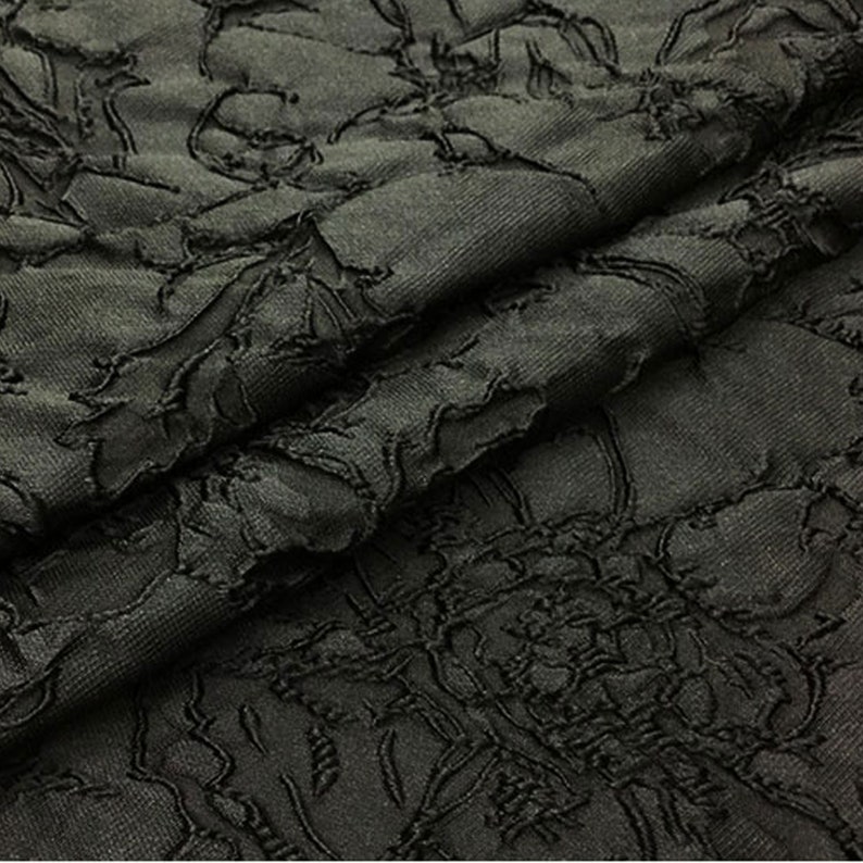 May include: Black fabric with a textured floral pattern. The fabric is soft and has a subtle sheen.