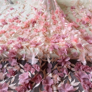 May include: Pink and gold floral lace fabric with 3D flowers. The fabric has a delicate, feminine look and would be perfect for a variety of projects, such as dresses, skirts, and tops.
