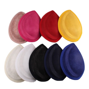 May include: A collection of teardrop-shaped hat bases in various colors, including pink, red, yellow, white, black, and blue. The bases have a textured fabric appearance, suitable for millinery projects or hat making.