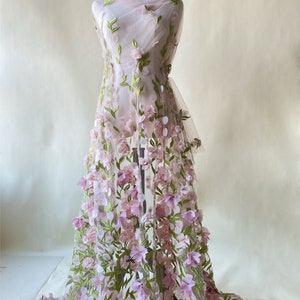 May include: Pink and green floral embroidered tulle fabric with 3D flowers. The fabric is sheer and delicate, with a soft, romantic feel.