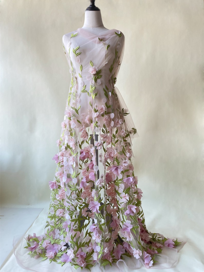 May include: Pink and green floral embroidered tulle fabric with 3D flowers. The fabric is sheer and delicate, with a soft, romantic feel.