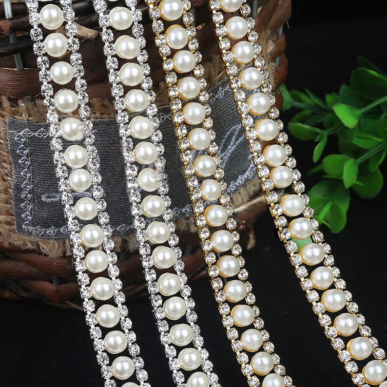 May include: Three strands of trim featuring alternating rows of faux pearls and clear rhinestones. The trim is available in silver, gold, and clear.