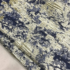 May include: Close-up of a textured fabric with a pattern of navy blue and gold. The fabric has a crinkled appearance, with diagonal lines and a mottled effect. The overall look is luxurious and elegant.