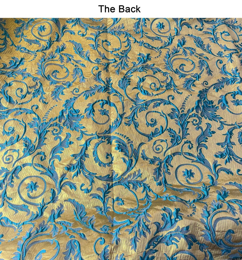 May include: A close-up of a fabric with a gold background and a blue floral pattern. The fabric has a textured, woven look.