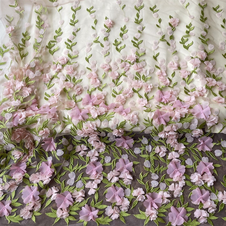 May include: Pink and green floral embroidered fabric with 3D flowers. The fabric has a delicate, sheer texture.