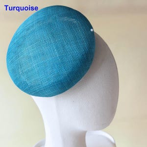 May include: A turquoise-colored, oval-shaped hat with a textured weave. The hat is displayed on a white mannequin head. The word "Turquoise" is printed in white on the upper left side of the hat.