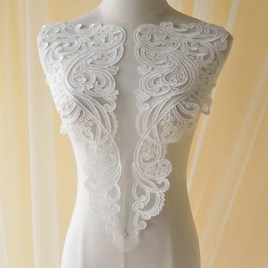 May include: White lace applique with a delicate floral pattern. The lace is designed for sewing onto clothing or other fabric projects.