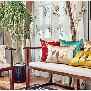 May include: A wooden bench with white cushions and several throw pillows featuring embroidered birds and floral designs. The pillows are in shades of red, yellow, blue, and green.