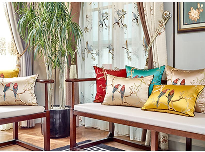 May include: A wooden bench with white cushions and several throw pillows featuring embroidered birds and floral designs. The pillows are in shades of red, yellow, blue, and green.