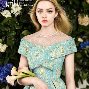 May include: A woman in a turquoise and gold patterned dress with a sheer neckline holds calla lilies. The image is from a magazine cover with the text "STYLISH gril" and "New season No.1 Special Issue."