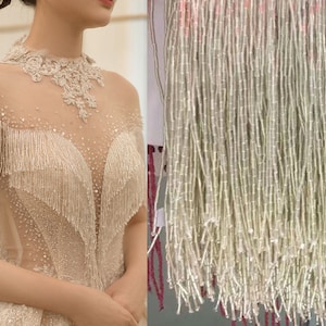 Pode incluir: Franja de contas brancas com uma textura delicada e brilhante. A franja é feita de pequenas contas redondas que são enfiadas para criar um efeito fluido e em cascata. Esta franja é perfeita para adicionar um toque de elegância e brilho a qualquer projeto.