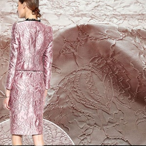May include: Pink brocade fabric with a floral embossed pattern. The fabric has a subtle sheen and a soft texture.
