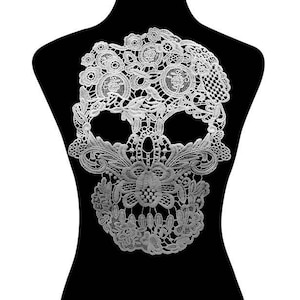 May include: White lace skull applique. The skull is detailed with intricate floral patterns and is perfect for adding a touch of gothic elegance to any project.