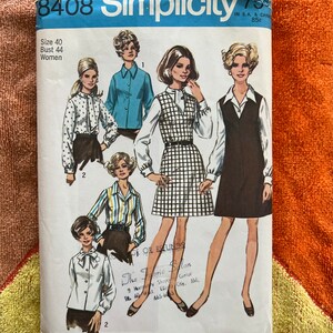 May include: A vintage Simplicity sewing pattern, number 8408, featuring illustrations of women's blouses and dresses. The pattern includes sizes for a bust of 44 inches. The package is white with blue and black text and illustrations.