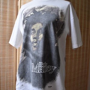 May include: White t-shirt with a black and white image of Bob Marley. The shirt has the text "Bob Marley" printed on the front.
