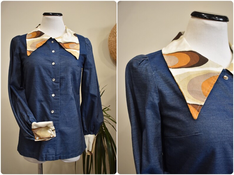May include: A blue denim shirt with a large, white, brown, and orange patterned collar. The collar has a geometric design.