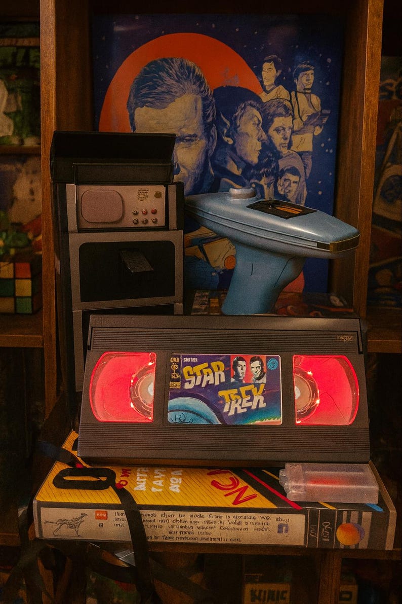 a Star Trek video tape, a vintage electronic device, and a Star Trek poster on a shelf.