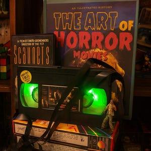 a collection of items related to horror movies, including a VHS tape, a book, and a toy.