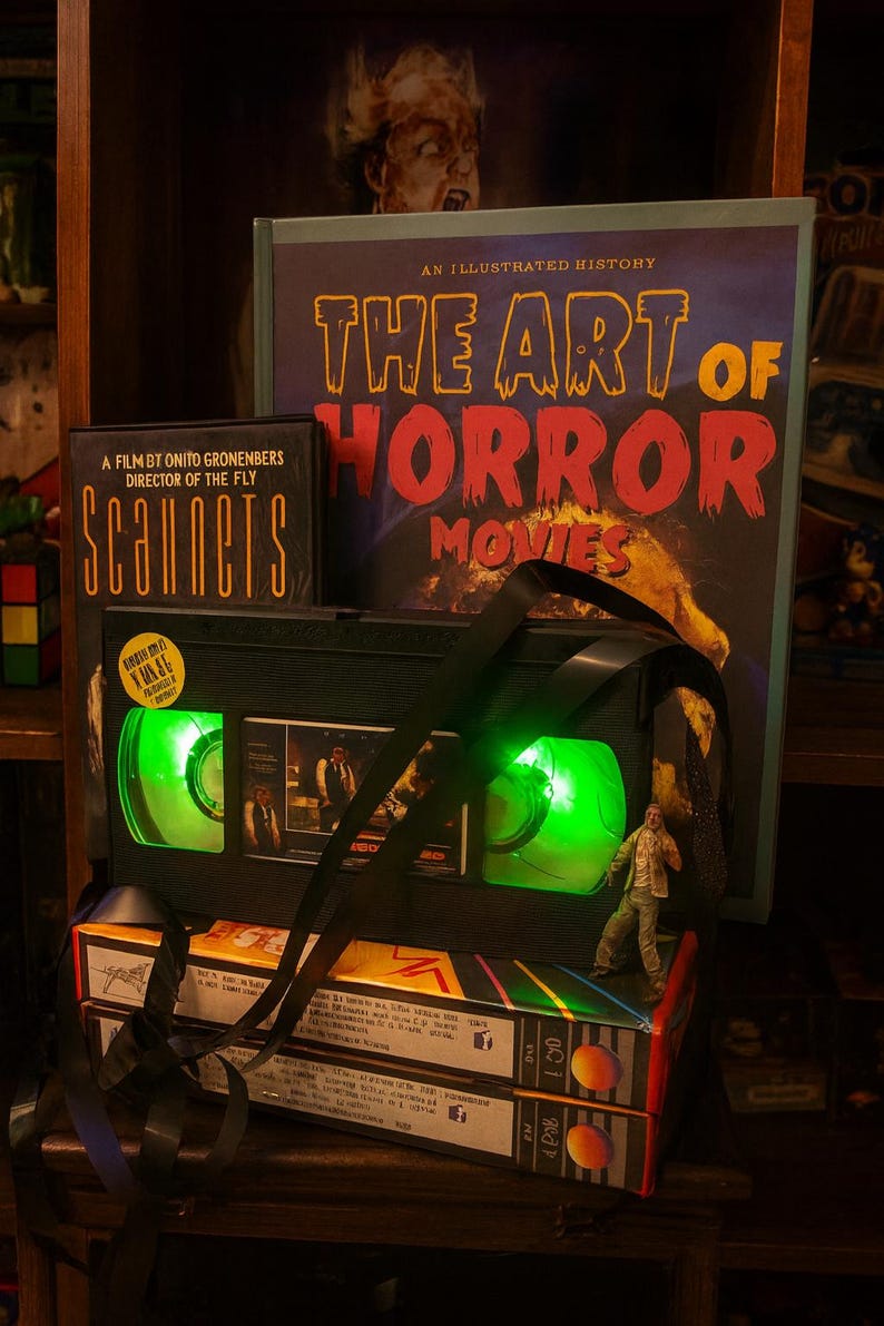 a collection of items related to horror movies, including a VHS tape, a book, and a toy.
