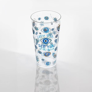 May include: A clear plastic drinking glass with a blue and white pattern of evil eyes and the text "See you at the beach".