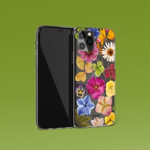 Może przedstawiać: Przezroczyste etui na telefon z kwiatowym wzorem z suszonych kwiat&oacute;w w r&oacute;żnych kolorach, w tym r&oacute;żowym, fioletowym, ż&oacute;łtym i zielonym. Etui jest kompatybilne z iPhonem 13 Pro.