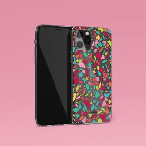May include: A clear phone case with a colorful terrazzo pattern. The case has a black background with pink, red, blue, green, and yellow accents. The case is designed for an iPhone with a camera bump.