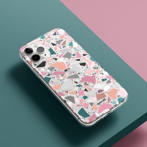 K&ouml;nnte beinhalten: Eine transparente Handyh&uuml;lle mit einem Terrazzo-Muster in Rosa-, Grau-, T&uuml;rkis- und Pfirsicht&ouml;nen. Die H&uuml;lle hat einen transparenten Rand und der Text "TALK & TELL" ist unten rechts aufgedruckt.