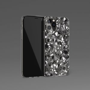 May include: A clear phone case with a black and white terrazzo pattern. The case has a raised camera bump and the text "Talis & Tell" is printed on the back.