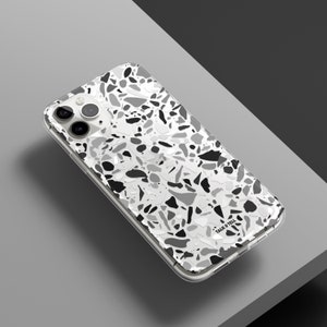 May include: A clear phone case with a black and white terrazzo pattern. The case has a "Talk & Tell" logo on the bottom right corner.