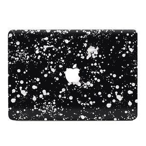 Puede incluir: Funda negra para portátil con diseño de salpicaduras de pintura blanca. El logotipo de Apple es visible en el centro. La funda tiene un acabado brillante y forma rectangular con esquinas redondeadas.