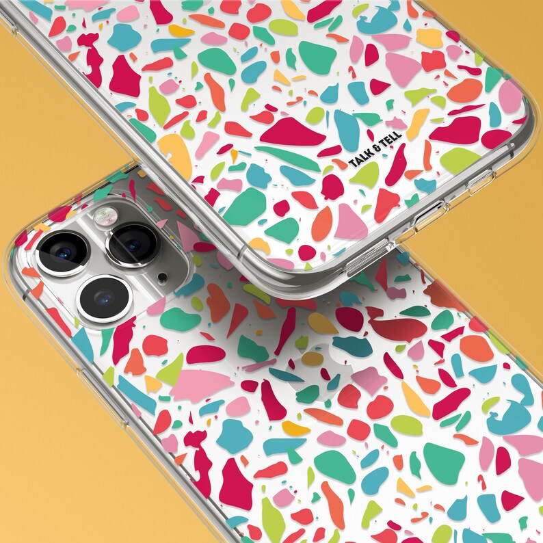 May include: A clear phone case with a colorful terrazzo pattern. The case has a white background with various shapes and colors, including red, pink, blue, green, and yellow. The text "Talk & Tell" is printed on the case.