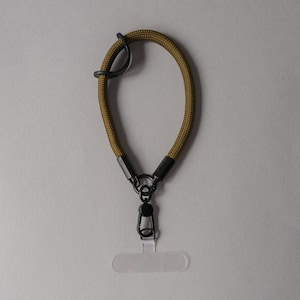 May include: A green and black camera strap with a metal clip and a clear plastic badge holder.