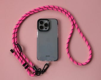 May include: A pink and black phone strap with a silver phone case attached. The phone case has a black camera lens with four lenses.