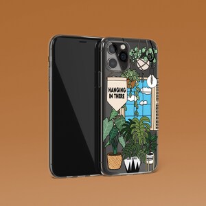 May include: A phone case featuring a colourful illustration of hanging plants in a window. The text "Hanging in there" is on a banner in the window.