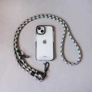 May include: A clear phone case with a black border and a colorful lanyard. The lanyard is made of a woven rope-like material with green, pink, and black accents. The phone case has the text "TALK & TEXT" at the bottom.