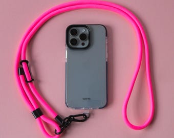 May include: A pink phone strap with a black phone case and a clear back. The phone case has a camera lens with four black circles. The text "TAKE IT ALL" is printed on the back of the phone case.
