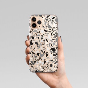 May include: A clear phone case with a black, white, and gray terrazzo pattern. The case has the text "Talk & Tell" printed on the bottom.
