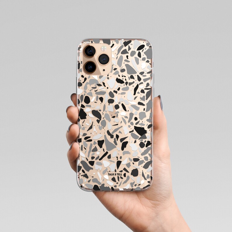 May include: A clear phone case with a black, white, and gray terrazzo pattern. The case has the text "Talk & Tell" printed on the bottom.