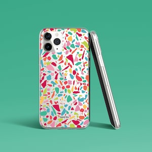 May include: A clear phone case with a colorful terrazzo pattern. The case has a white background with red, orange, yellow, green, blue, and pink terrazzo pieces. The case has the words "Talk & Tell" printed on the bottom.
