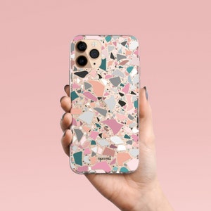 K&ouml;nnte beinhalten: Eine transparente Handyh&uuml;lle mit Terrazzo-Design. Die H&uuml;lle zeigt ein Muster aus unregelm&auml;&szlig;igen Formen in Rosa, Grau, T&uuml;rkis und Schwarz auf hellpfirsichfarbenem Hintergrund. Die Worte "TALK & TELL" sind unten aufgedruckt.