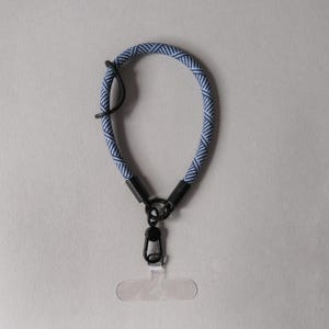 May include: A blue and black patterned lanyard with a black metal clip and a clear plastic badge holder.
