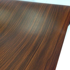 May include: A close-up of a brown woodgrain contact paper roll. The paper has a realistic woodgrain pattern.